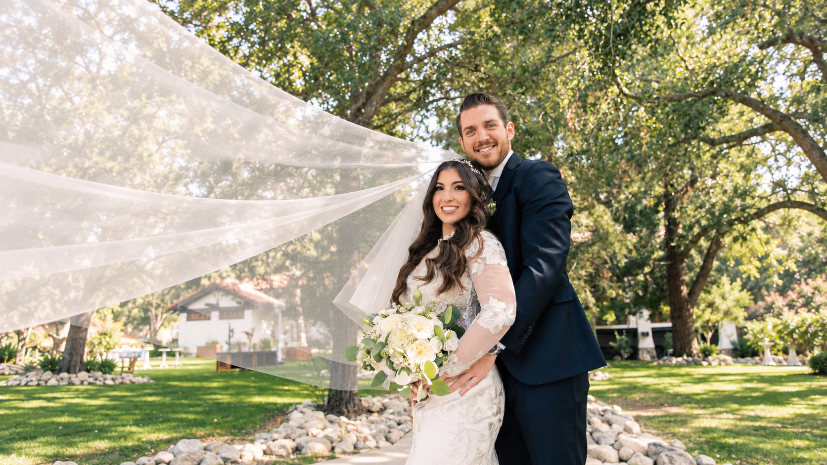 Bride and groom in a garden with the veil sweeping through the air, photographed by Shimmy Lautman